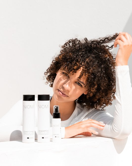 Woman with curly hair interacting with NIOMI hair care