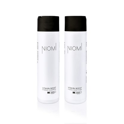 Two NIOMI Vitamin Boost hydrate hair care bottles on a white background