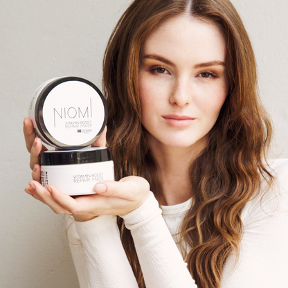 NIOMI Vitamin Boost Repair Mask packaging with product visible inside. Used by model