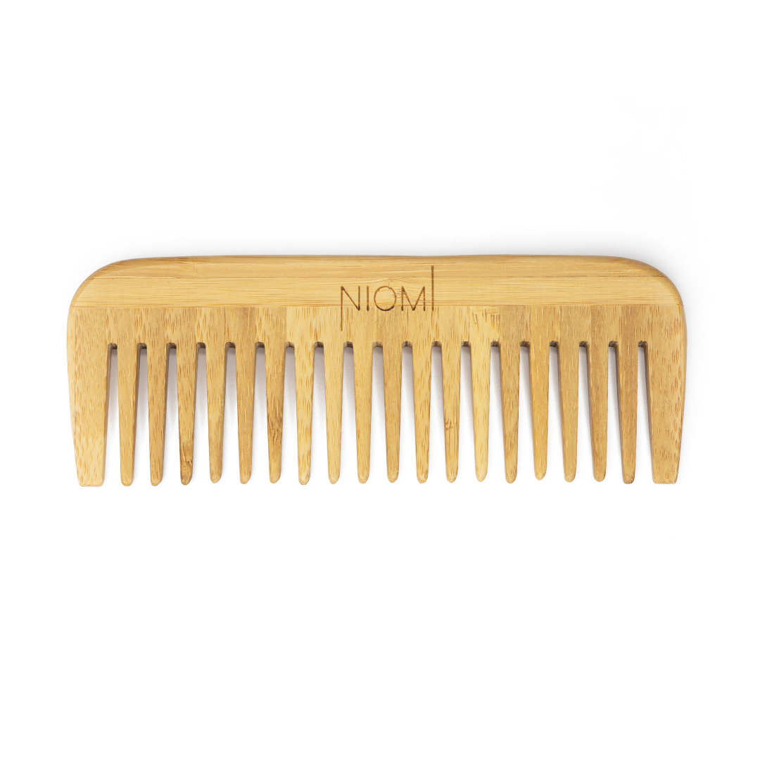 A bamboo detangling comb with the brand name 'NIOMI' inscribed on the flat edge.