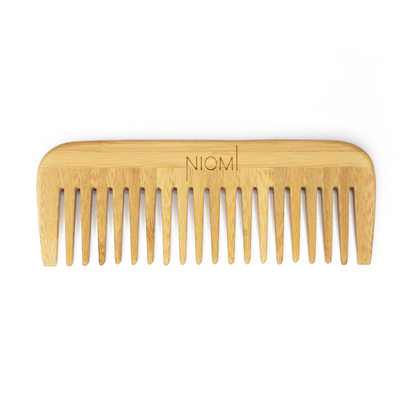 A bamboo detangling comb with the brand name 'NIOMI' inscribed on the flat edge.