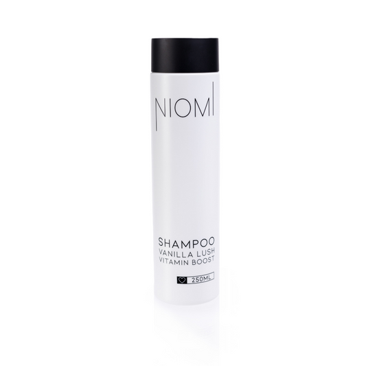 A bottle of NIOMI Vanilla Lush, Vitamin Boost Shampoo 250ml with a white label and black cap.