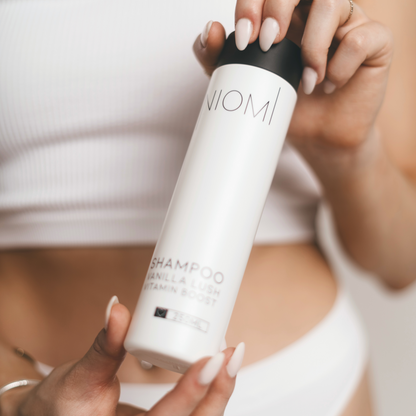 A bottle of NIOMI Vanilla Lush, Vitamin Boost Shampoo 250ml with a white label and black cap.


